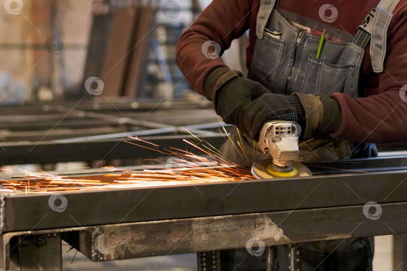 Скачать Руки рабочего, работающего угловой шлифовальной машиной с летящими искрами фотосток Ozero