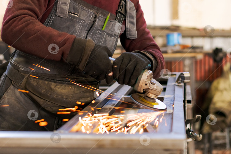 Скачать Торс слесаря с угловой шлифовальной машиной и яркими искрами фотосток Ozero