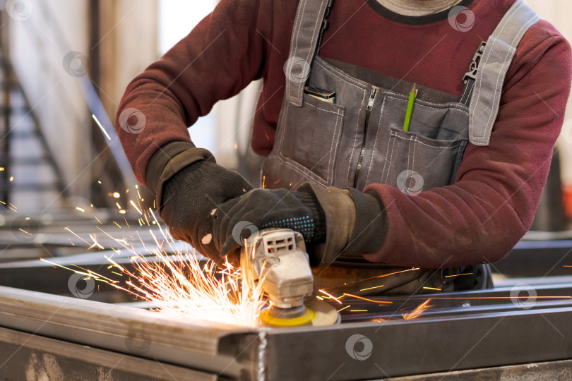 Скачать Руки промышленного рабочего, шлифующего металл с летящими искрами фотосток Ozero