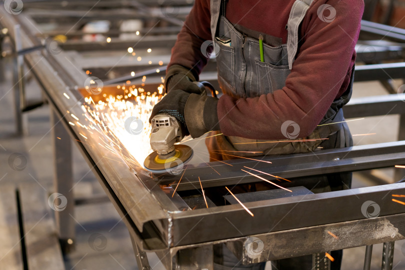 Скачать Руки квалифицированного рабочего Шлифуют сталь с интенсивным искрообразованием фотосток Ozero