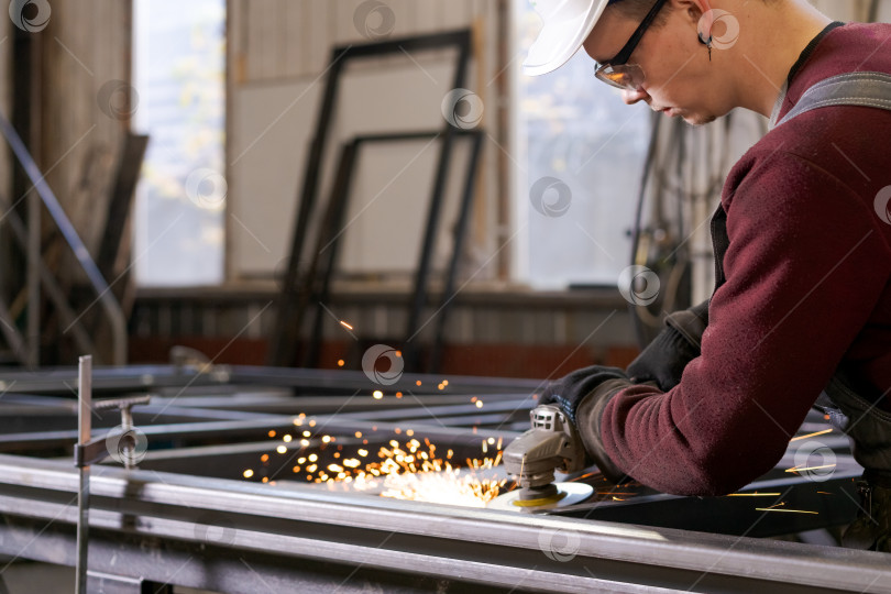Скачать Рабочий-строитель, шлифующий металлическую раму, Вид профиля фотосток Ozero