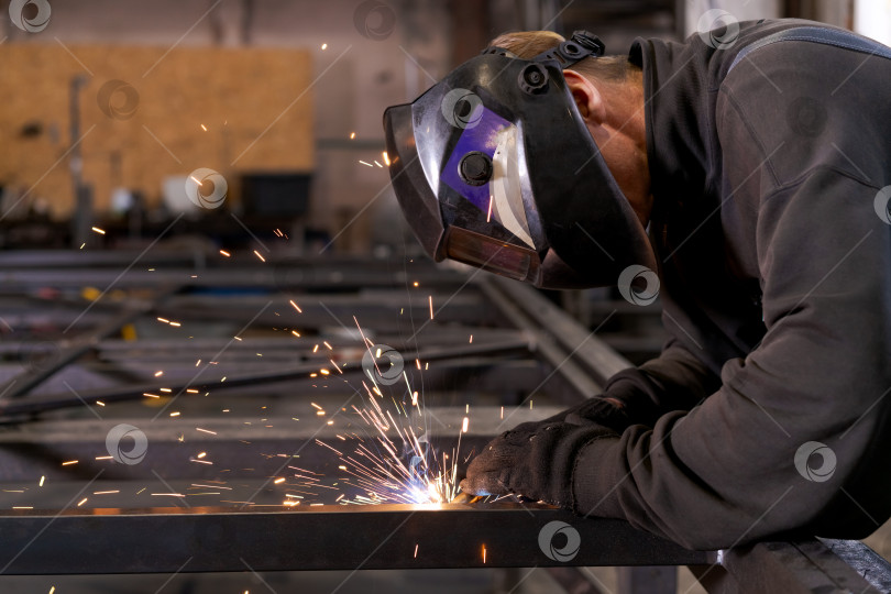 Скачать Профессиональный сварщик, выполняющий сварку металлических конструкций, Вид в профиль фотосток Ozero