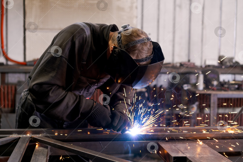 Скачать Опытный сварщик, создающий поток искр на металлическом каркасе фотосток Ozero