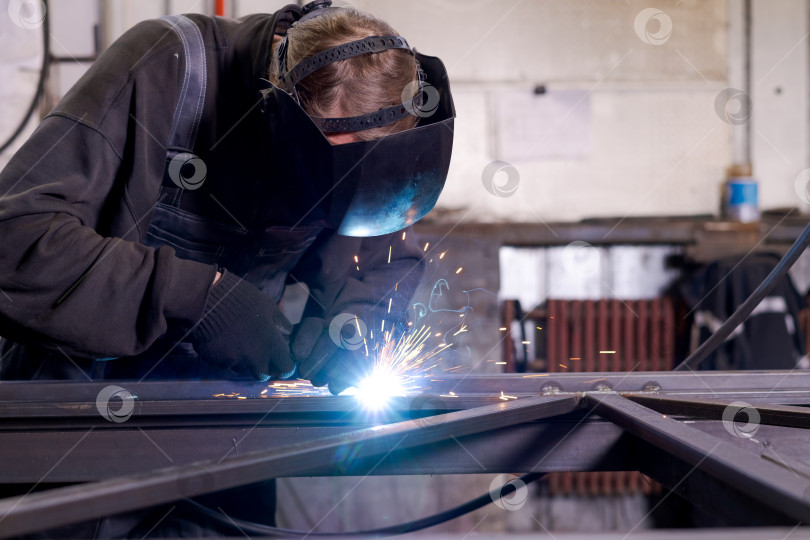 Скачать Старший сварщик, выполняющий сварку стали яркой дугой с радиатором позади фотосток Ozero