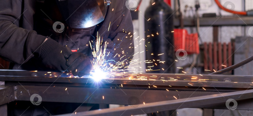 Скачать Корпус промышленного сварщика с искрами и газовым баллоном сзади фотосток Ozero