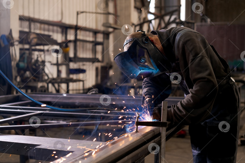 Скачать Сварщик, работающий со сталью с синим шлангом и искрами фотосток Ozero
