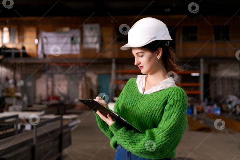 Скачать Женщина-инспектор что-то пишет в блокноте на складе металлолома фотосток Ozero