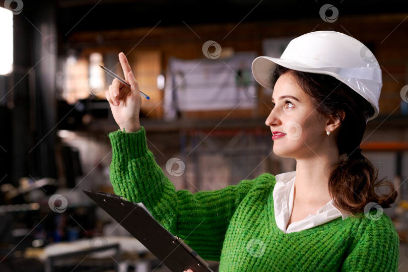 Скачать Женщина-инженер указывает вверх на промышленный склад фотосток Ozero