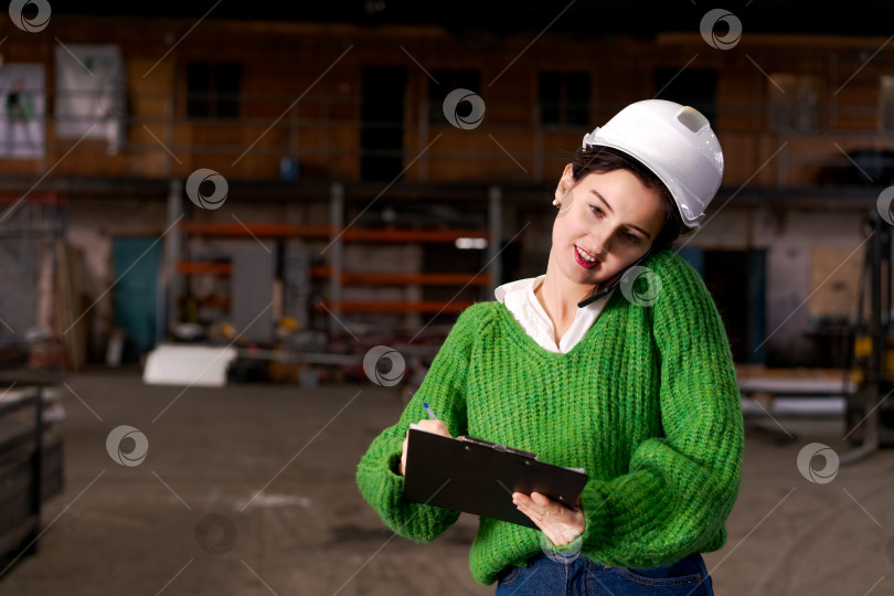 Скачать Женщина-инженер, работающая в режиме многозадачности с телефоном и буфером обмена фотосток Ozero