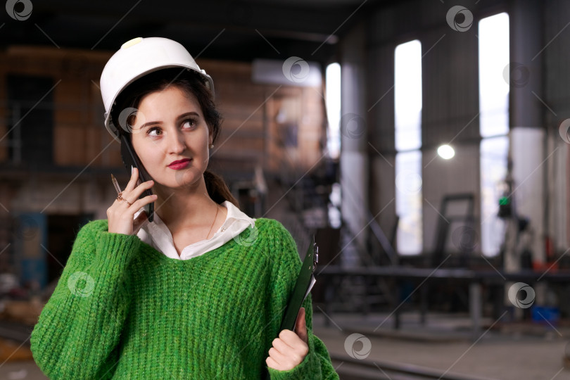 Скачать Женщина-инженер слушает телефонный разговор на металлическом складе фотосток Ozero