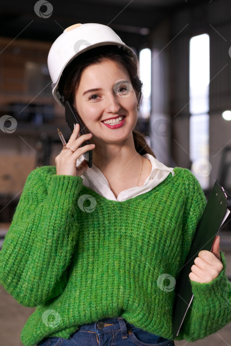 Скачать Женщина-инженер улыбается во время телефонного звонка на складе фотосток Ozero