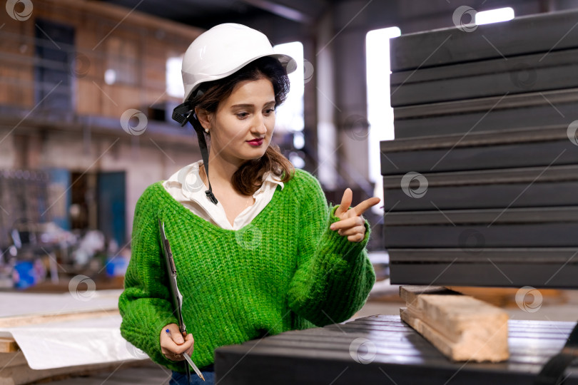 Скачать Женщина-инспектор подсчитывает металлические профили на складе фотосток Ozero