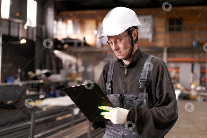 Скачать Рабочий завода читает документы на складе металлолома фотосток Ozero