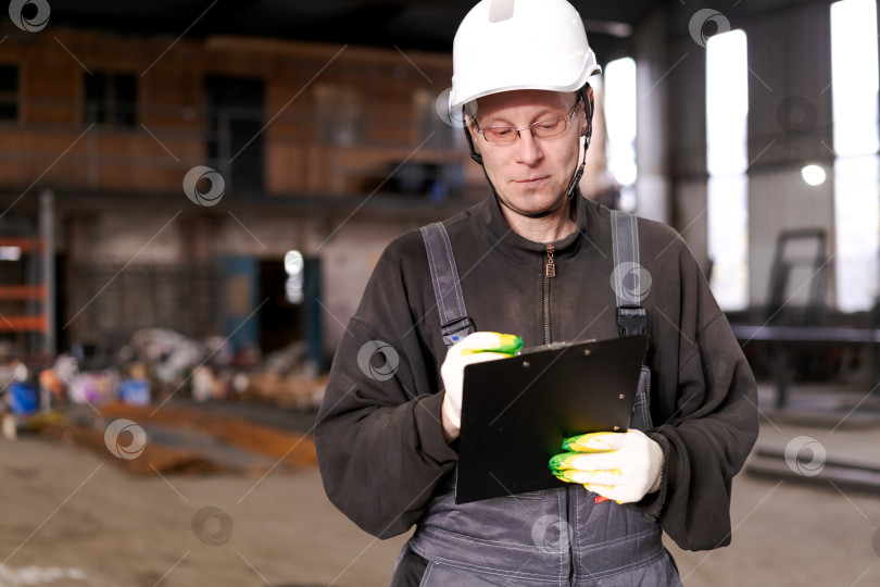 Скачать Мужчина-инспектор читает документы на складе металлолома фотосток Ozero