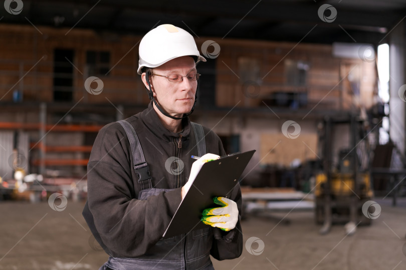 Скачать Фабричный рабочий делает заметки в буфере обмена фотосток Ozero