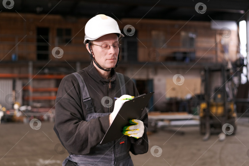 Скачать Мужчина-инспектор делает пометки на складе металлолома фотосток Ozero