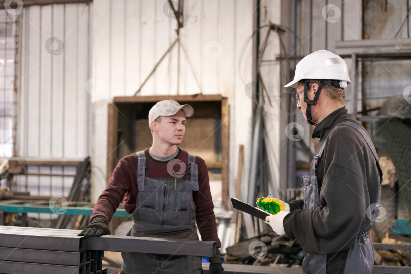 Скачать Руководитель инструктирует молодого рабочего на складе металлолома фотосток Ozero