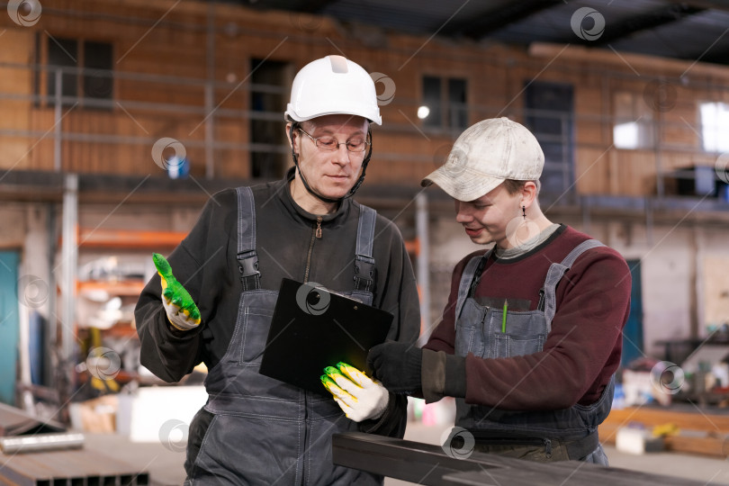 Скачать Старший работник обучает молодого коллегу на складе фотосток Ozero