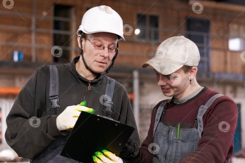 Скачать Наставник и стажер рассматривают план работы на заводе фотосток Ozero