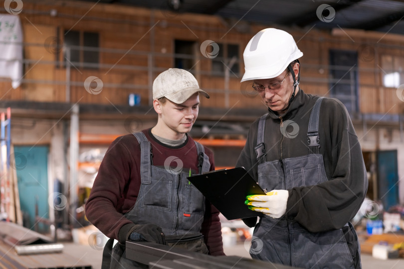 Скачать Двое рабочих просматривают буфер обмена на складе металлолома фотосток Ozero