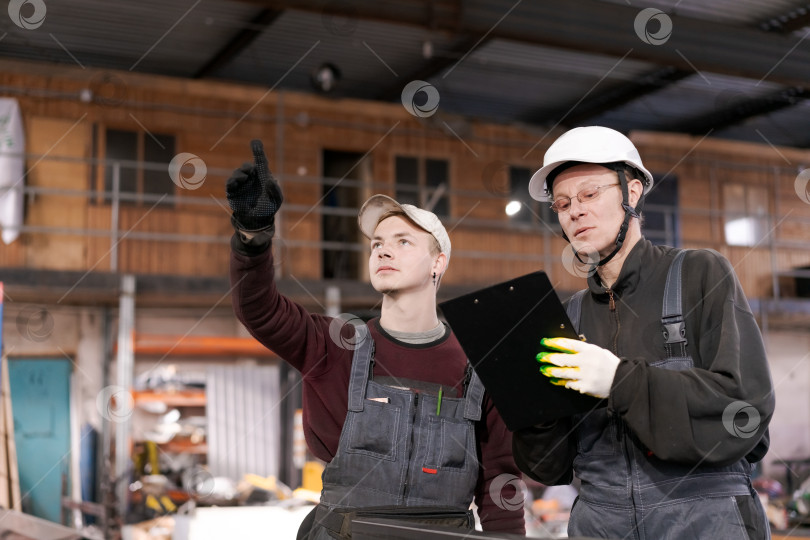 Скачать Молодой рабочий указывает вверх на промышленный склад фотосток Ozero