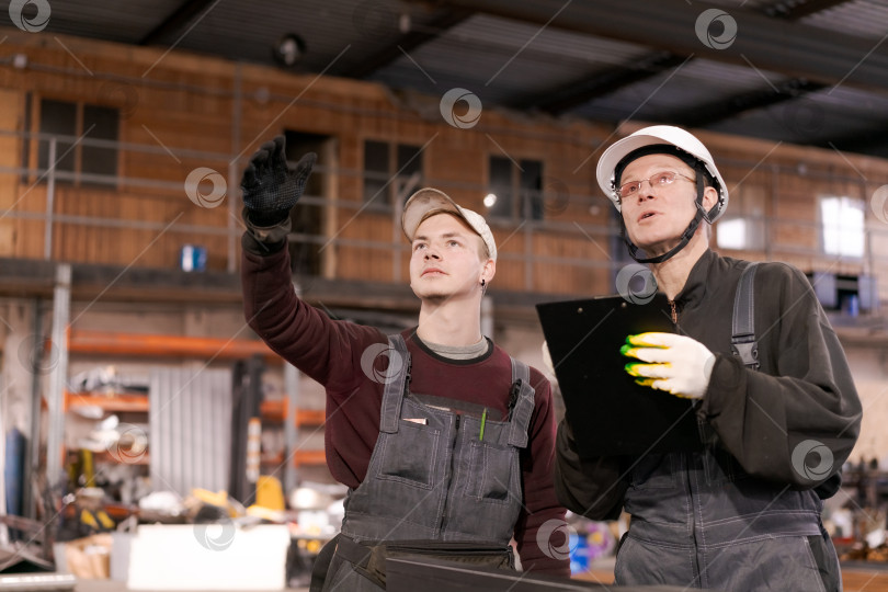 Скачать Фабричные рабочие смотрят на потолок склада фотосток Ozero