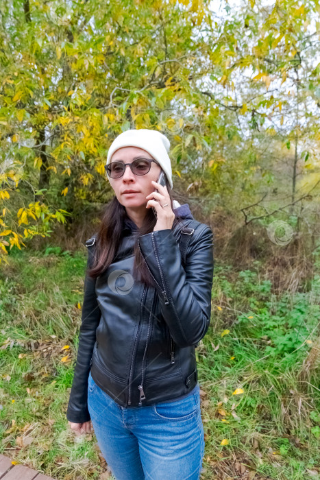 Скачать Женщина разговаривает по телефону в Осеннем парке фотосток Ozero