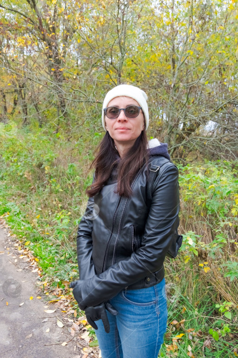 Скачать Женщина в кожаной куртке стоит в осеннем парке фотосток Ozero