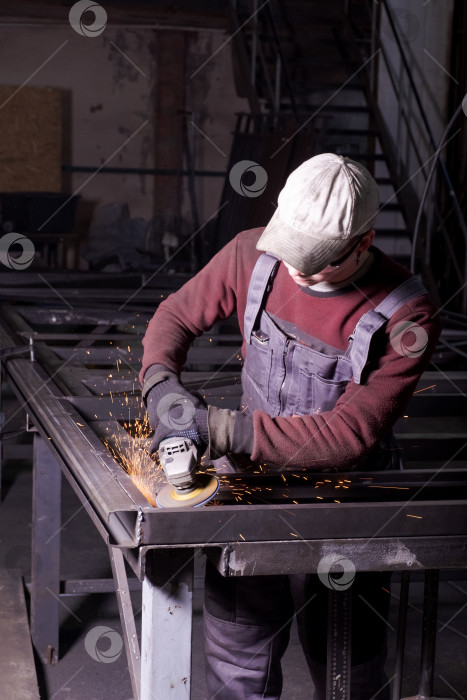 Скачать Молодой Рабочий Шлифует Металлическую Раму Угловой шлифовальной машиной фотосток Ozero