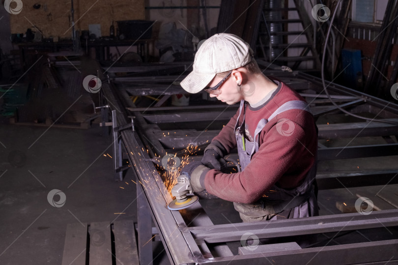 Скачать Слесарь, использующий угловую шлифовальную машину на стальной раме фотосток Ozero