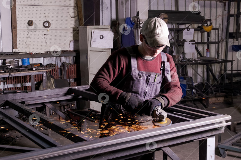 Скачать Молодой рабочий, шлифующий металл в мастерской фотосток Ozero