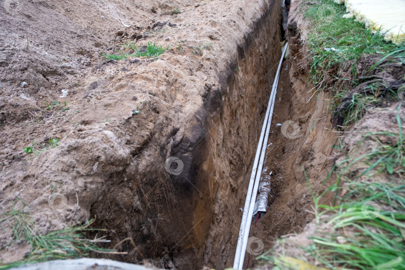 Скачать Выкопанная траншея для изолированной водопроводной трубы, сантехническое строительство, монтаж инженерных коммуникаций, защита трубопроводов, фундамент для труб в доме. фотосток Ozero