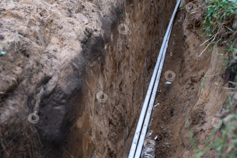 Скачать Заглубленные водопроводные трубы в траншее, изолированный подземный трубопровод, бытовая сантехника, земляной канал, фундамент для инженерных коммуникаций дома и теплозащиты. фотосток Ozero
