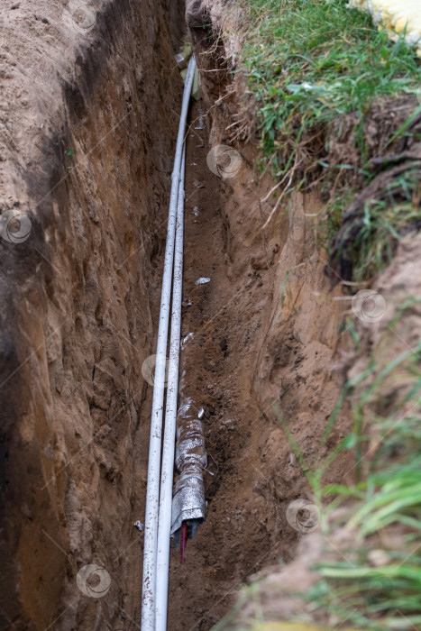 Скачать Копка глубокой траншеи для водопровода, прокладка изолированных труб, тепловая защита сантехники, место установки, подготовка фундамента для подключения инженерных сетей к дому. фотосток Ozero