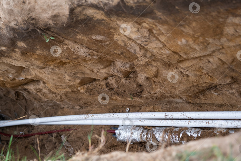 Скачать Изолированный трубопровод в грунтовой траншее, линия водоснабжения, наружные инженерные сети, земляные работы на стройплощадке, защита труб, бытовая сантехника, канал теплоизоляции. фотосток Ozero