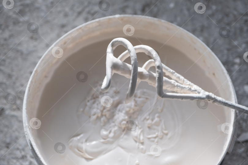 Скачать Смешивание штукатурки и шпаклевки с помощью перфоратора-миксера, подготовка к строительству, ремонт здания, равномерная консистенция для отделки стен и ремонтных работ. фотосток Ozero