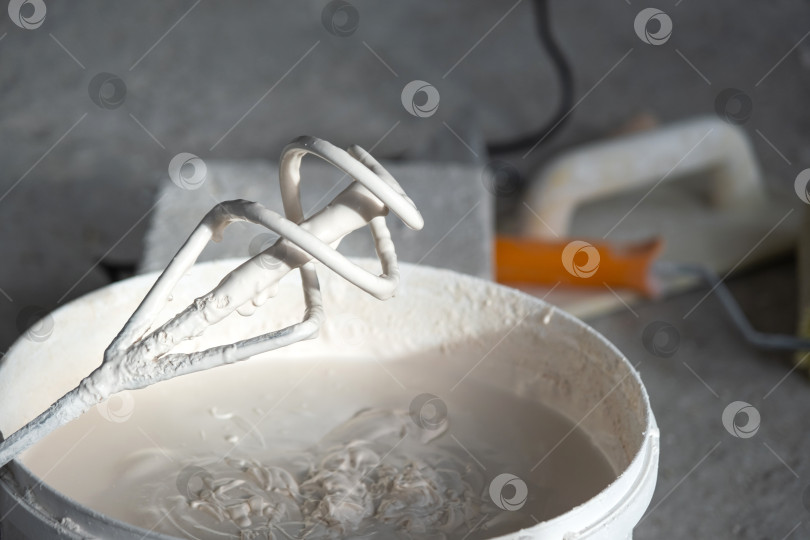 Скачать Сухая шпаклевочная масса в ведре для смешивания, готовая для использования в электрическом миксере, для подготовки конструкции, штукатурной смеси, на этапе ремонта стен и реновации, для отделочных работ. фотосток Ozero