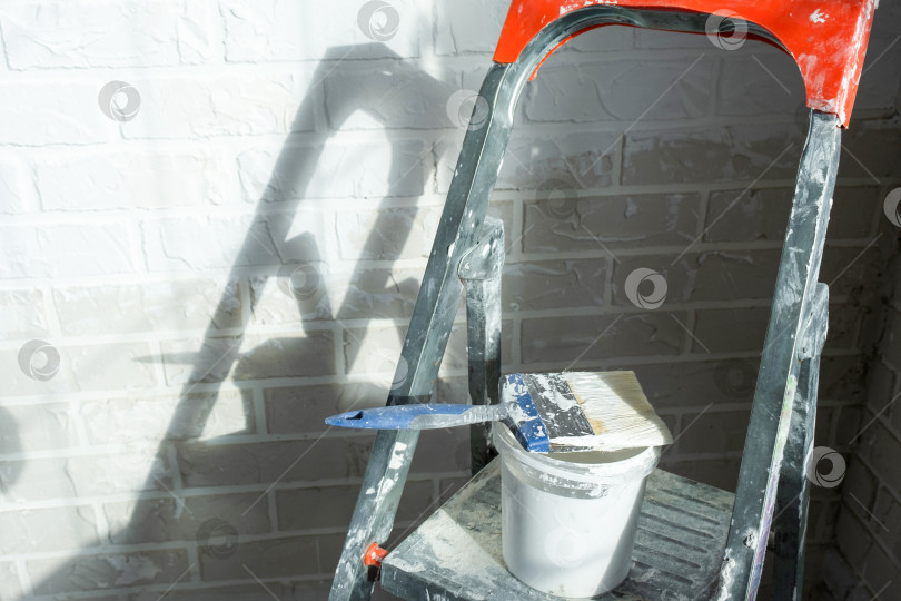 Скачать Набор малярных принадлежностей, стремянка и ведро с краской для ремонта интерьера, подготовки стен к отделке дома, улучшения внешнего вида помещения. фотосток Ozero