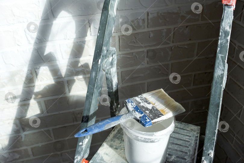 Скачать Продолжается обновление отделки стен, малярные принадлежности и инструменты, рабочее место со стремянкой, проект благоустройства дома, декор интерьера, ремонтные работы в помещении. фотосток Ozero