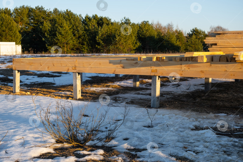 Скачать Основание деревянного каркаса на сваях, ранняя стадия строительства, монтаж конструкции, деревянные балки, процесс монтажа каркаса, плотницкие работы, деревянный фундамент, наружная рабочая площадка. фотосток Ozero