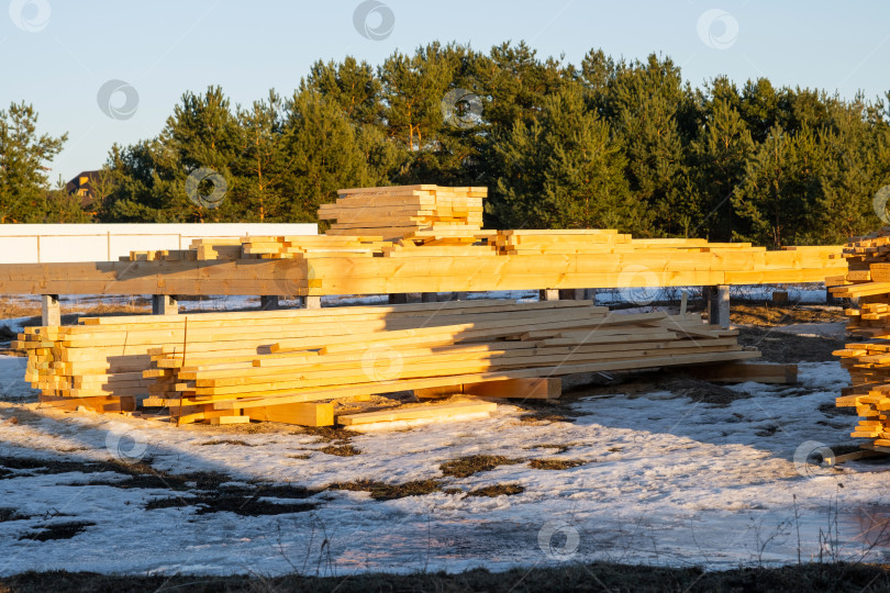 Скачать Заготовка пиломатериалов для деревянного дома, подготовка к строительству деревянного каркаса, строительные материалы, балки, доски, укладываемые в штабеля для использования, сборка на месте, современный проект. фотосток Ozero