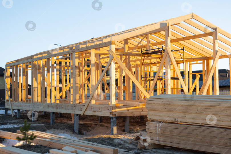 Скачать Деревянные стойки и балки, собранные для каркасного дома, деревянный каркас, монтажное основание, ход строительства, опорные элементы площадки, установка внешнего фундамента. фотосток Ozero
