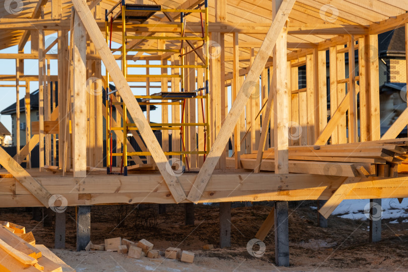 Скачать Вид фундамента деревянного каркасного дома, деревянные балки, опоры конструкции, столярные работы, каркас на сваях, монтаж и стяжка, рабочее место, монтажная площадка. фотосток Ozero