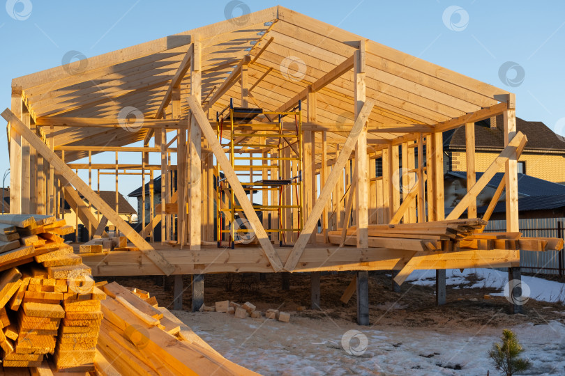 Скачать Сборка каркасного дома, деревянный каркас, балки, стойки на месте, крепежные элементы, опоры для фундамента, современные столярные работы, ход строительства на стройплощадке, монтаж. фотосток Ozero
