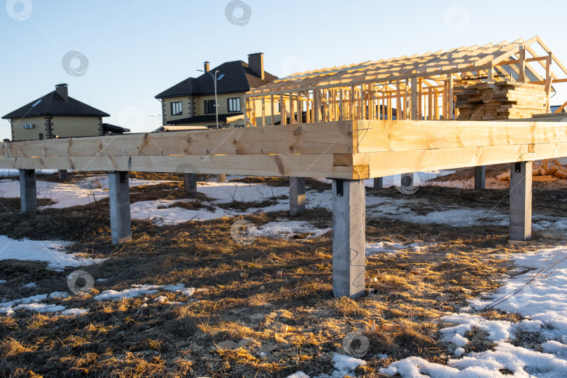 Скачать Фундамент деревянного дома установлен на винтовых сваях, виден фундамент, ведется монтаж каркаса, подготовка площадки, строительство площадки, первый этап, столярные работы. фотосток Ozero
