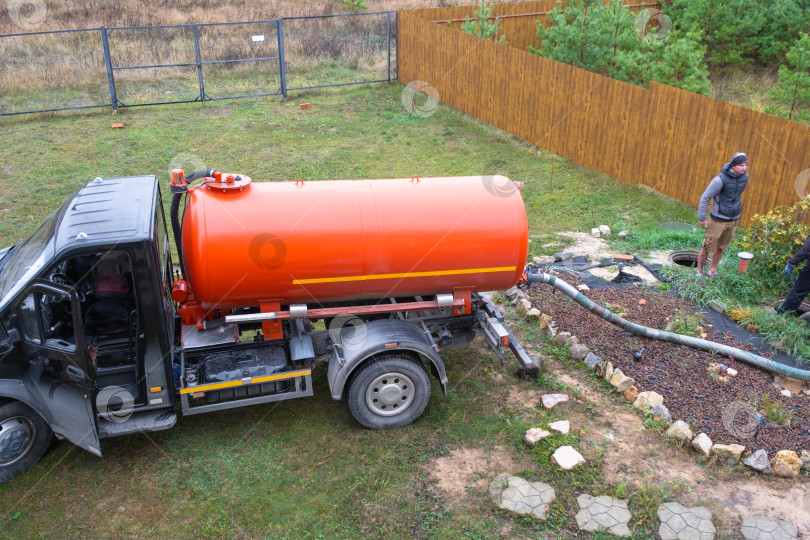 Скачать Ассенизаторская машина на загородной территории, откачивающая септик, профессиональное управление отходами, их вывоз и экологичная утилизация в частных домах. фотосток Ozero