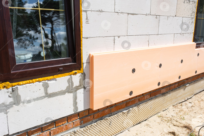 Скачать Утепление фасада здания пенопластом, наружная облицовка стен, ремонт дома, строительная площадка, энергоэффективность, ремонт фасада, монтаж панелей. фотосток Ozero