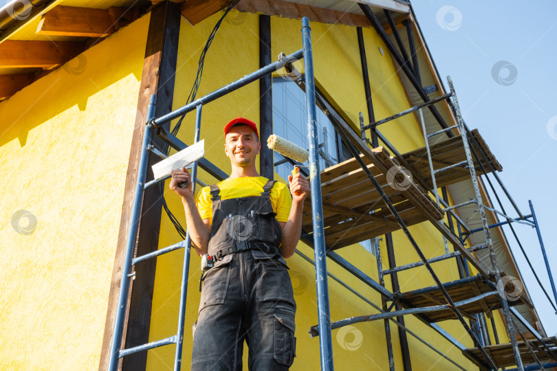 Скачать Строитель с малярным валиком, ремонт фасада, строительные леса, ремонтные работы, инструменты, услуги разнорабочего по благоустройству дома, консультация, специалист по отделочным работам. фотосток Ozero