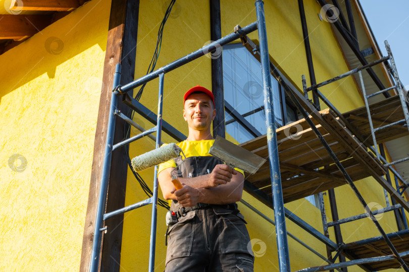Скачать Мастер-ремонтник с роликом на строительных лесах, наружная покраска, ремонт стен, инструменты для разнорабочего, ремонт фасадов, обслуживание на дому, мастерство бригады, консультационный звонок. фотосток Ozero