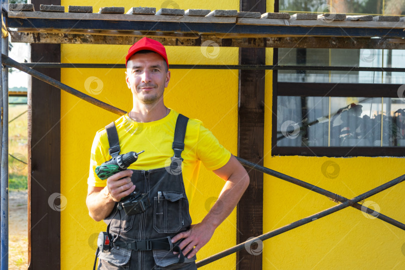 Скачать Портрет строителя с дрелью в спецодежде, строительство нового дома, частный бизнес разнорабочего, работа "сделай сам", обустройство дома, специалист по инструментам, визит к клиенту. фотосток Ozero